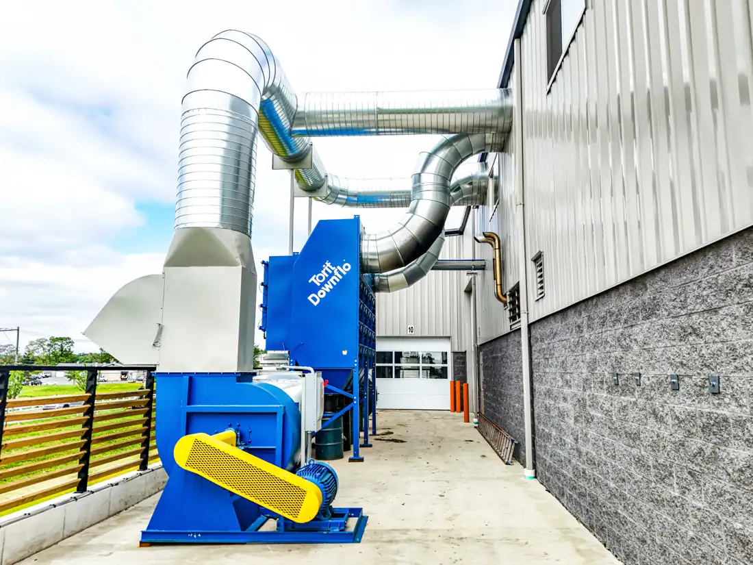 Exterior dust collector and blower connected to spiral ductwork at a fabrication shop | CSI Collector Systems - Dust & Fume Collection Systems